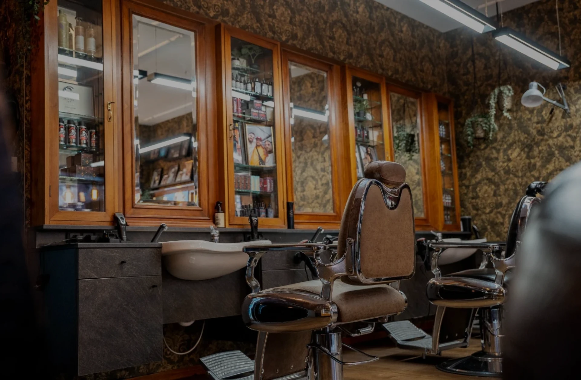 Klassische Barberstühle vor warmen Holzschränken im GOAT Barbershop